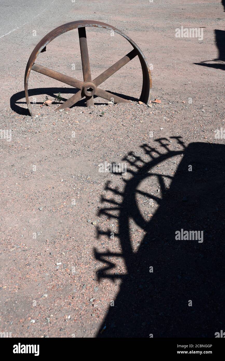 Ein Metallschild vor dem Restaurant und der Bar Mine Shaft in Madrid, New Mexico, wirft einen Schatten auf den Wüstenboden. Stockfoto
