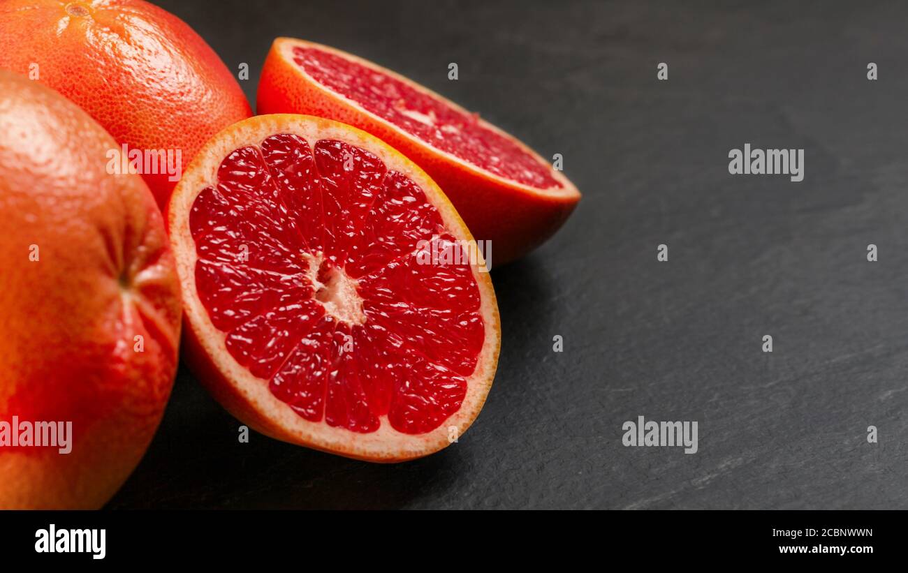 Rosa Grapefruits, eine Zitrusfrucht halbiert, auf schwarzem schieferartigen Brett Stockfoto