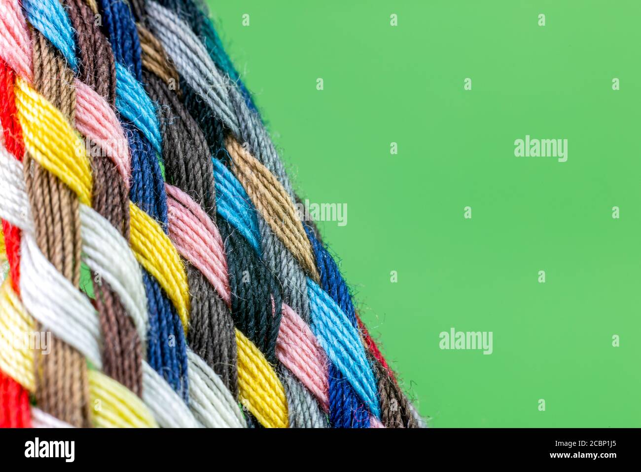 Streifen aus geflochtenen farbigen Baumwollfäden mit grünem Hintergrund Stockfoto