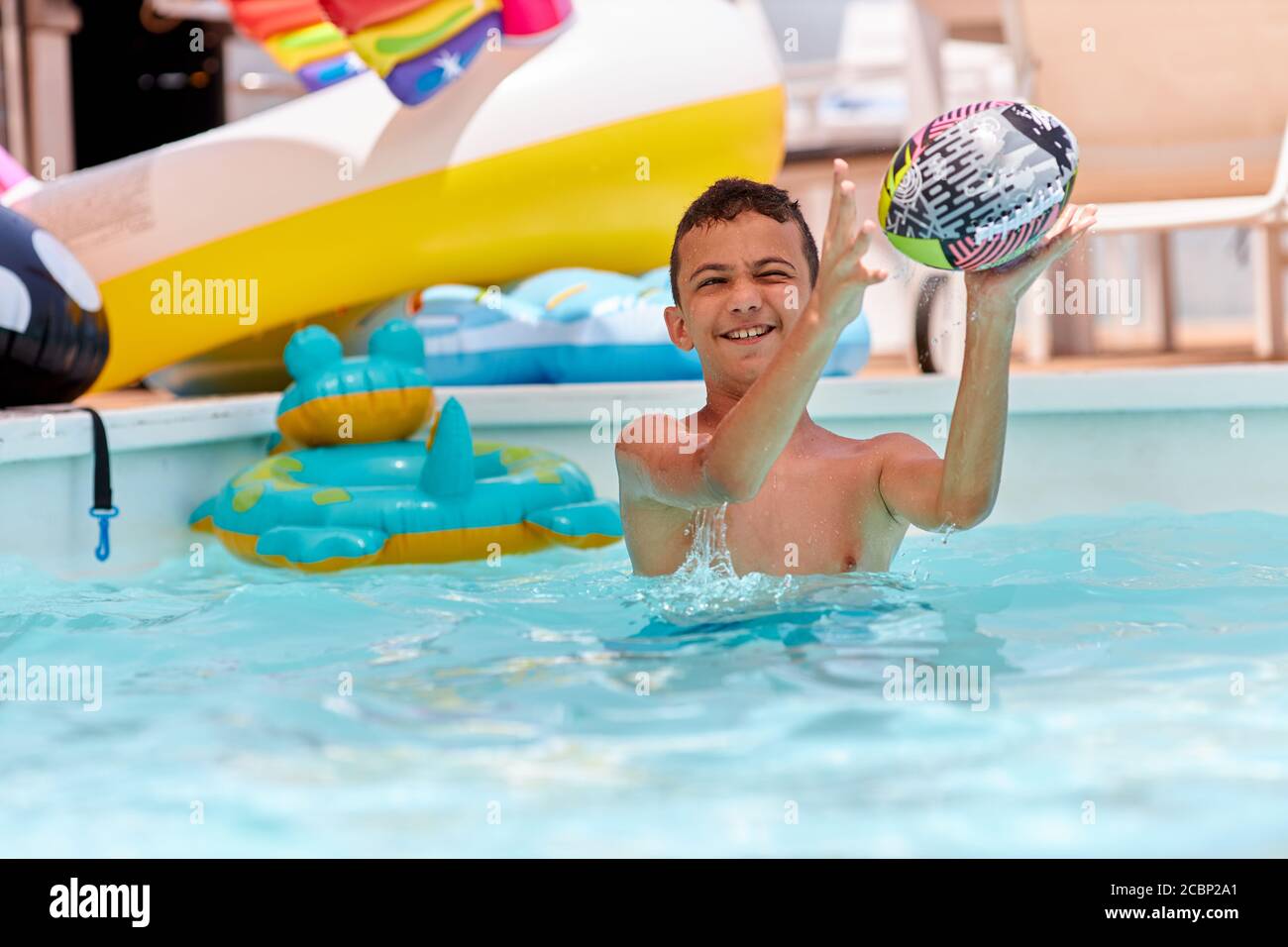 Junge spielt mit Bällen am Pool Stockfoto