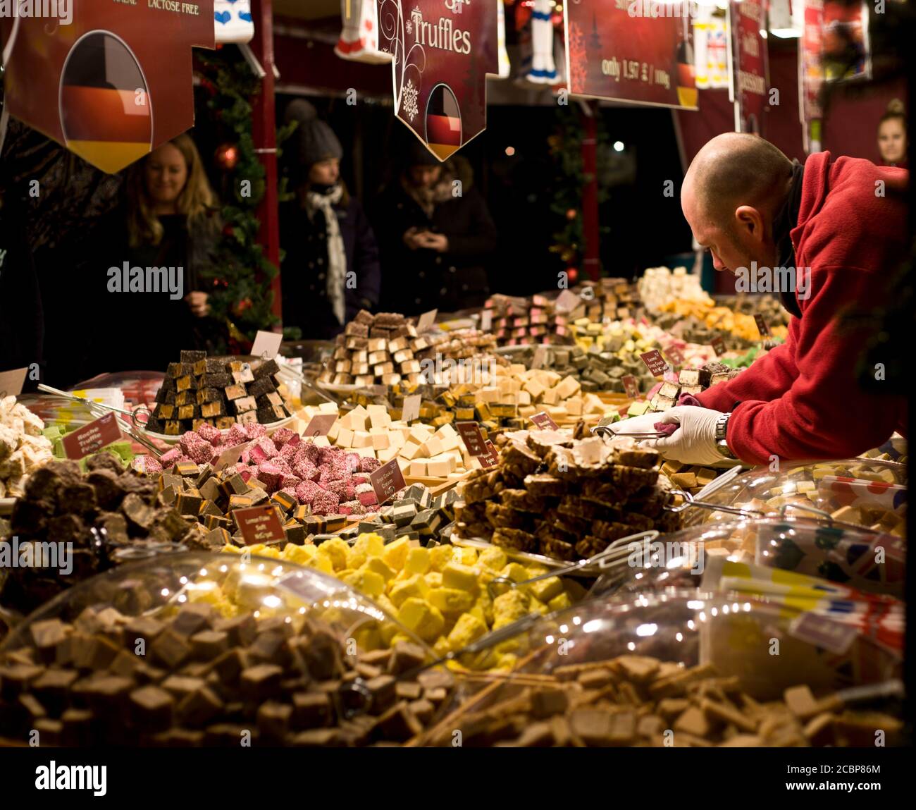 Ein Straßenverkäufer bedient sich an seinem Pick-n-Mix-Stand, während die Kunden warten. Süßigkeiten, deutsch, Markt, Stand, Süßigkeiten, Süßwaren, gemischt, Street Photography Stockfoto
