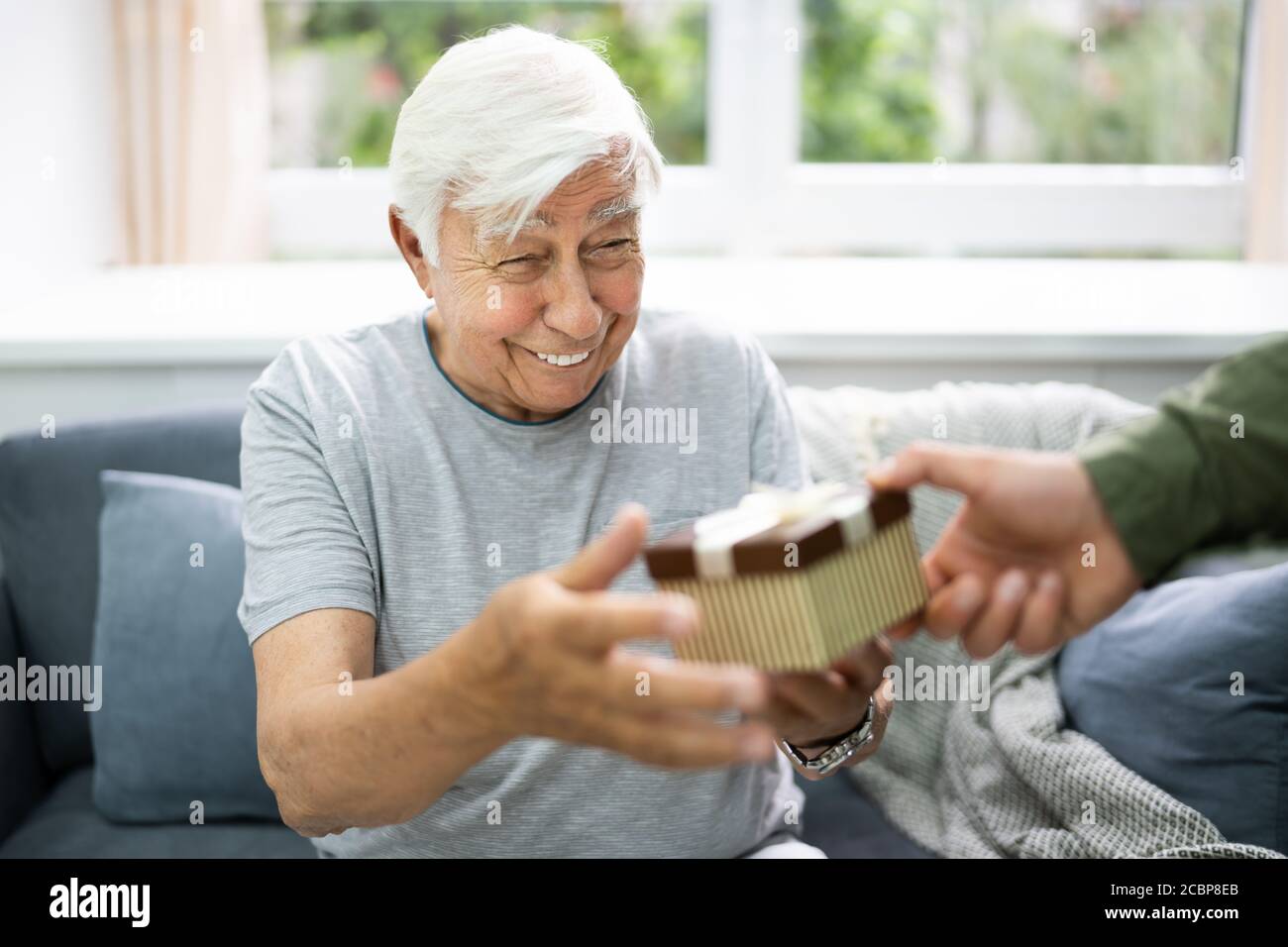 Seniorbürger, Der Ein Festgeschenk Im Pflegeheim Erhält Stockfoto
