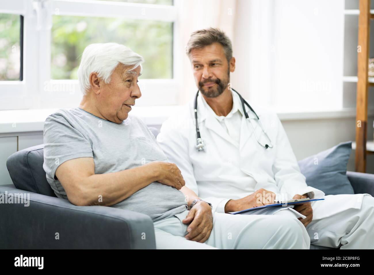 Der Ältere Patient Der Hauspflege Spricht Mit Seinem Arzt Stockfoto