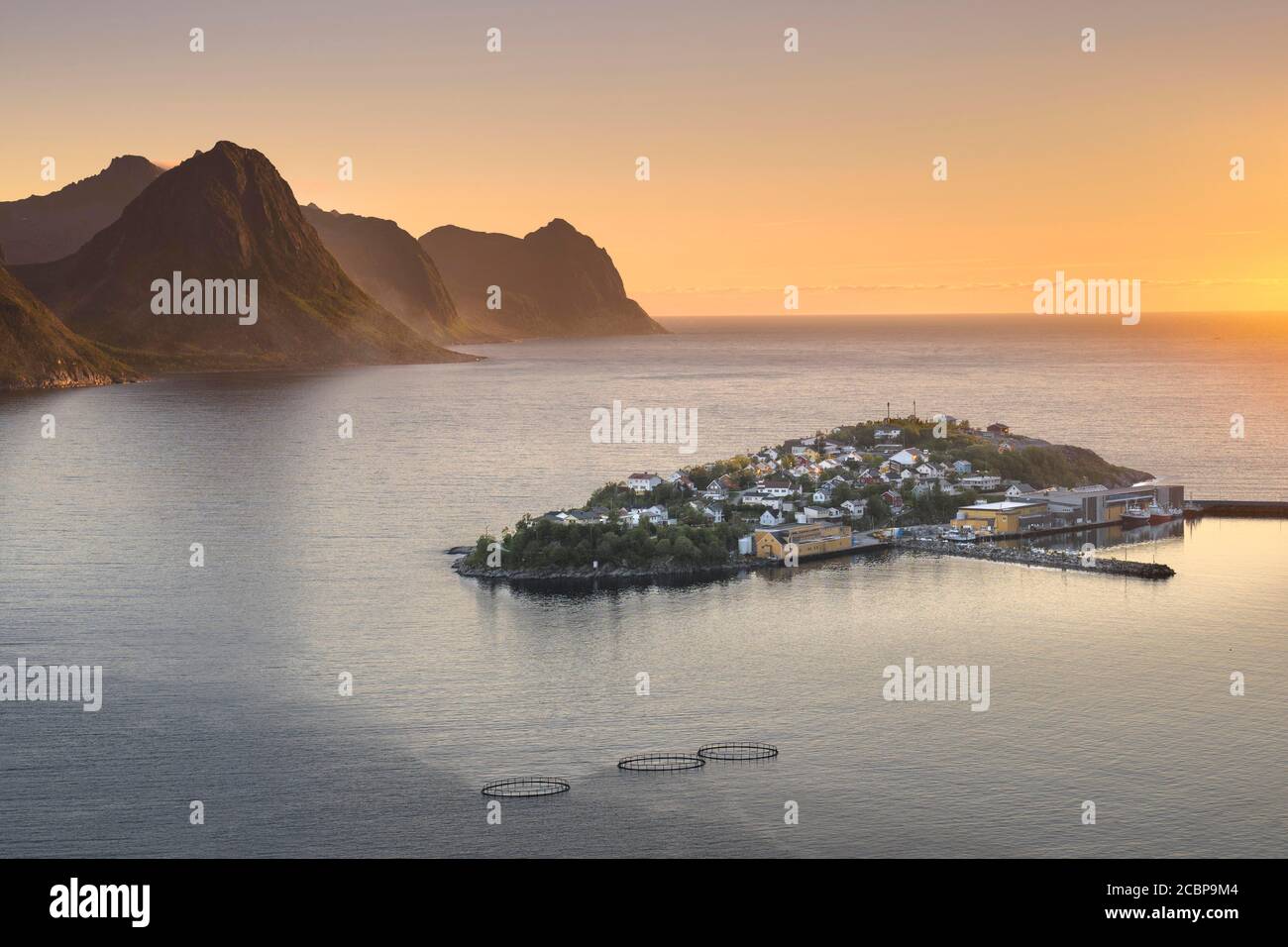 Insel mit Ort Husoy im Fjord bei niedriger Sonne mit stimmungsvollem Licht, Insel Senja, Husoy, Troms, Norwegen Stockfoto