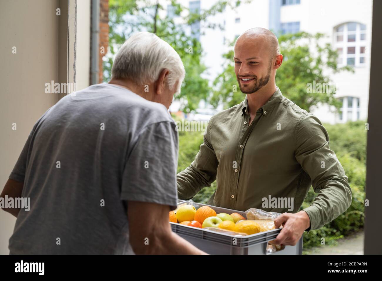 Hilfe Beim Einkaufen Von Lebensmitteln Für Älteren, Der Vor Der Tür Steht Stockfoto