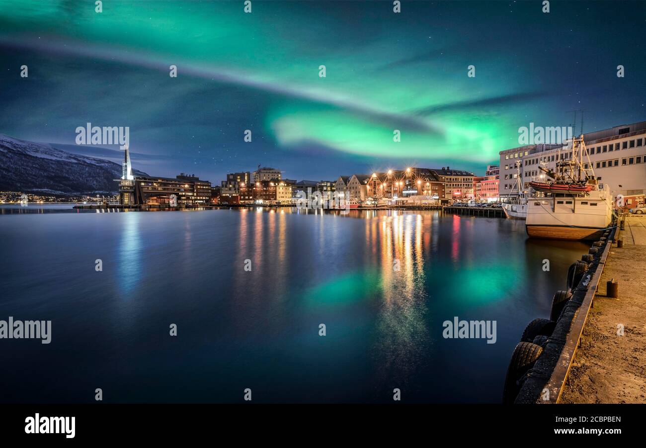 Nordlichter über Stadt und Hafen mit Spiegelung im Meer, Tromsoe, Troms, Norwegen Stockfoto