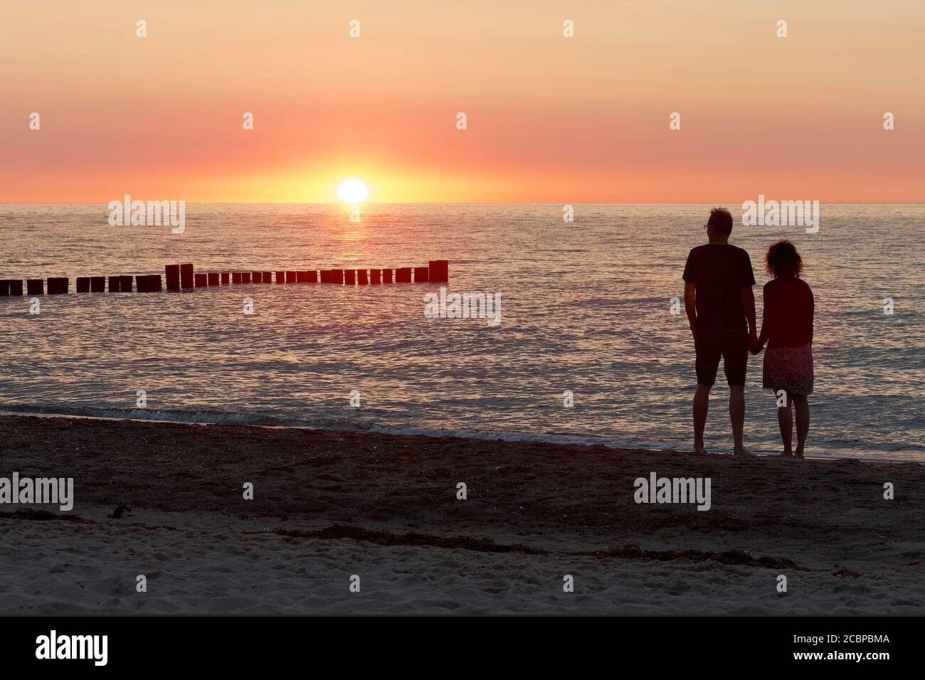 Ehepaar hält sich die Hände und beobachtet den Sonnenuntergang an der Ostsee, Kühlungsborn, Mecklenburg-Vorpommern, Deutschland Stockfoto