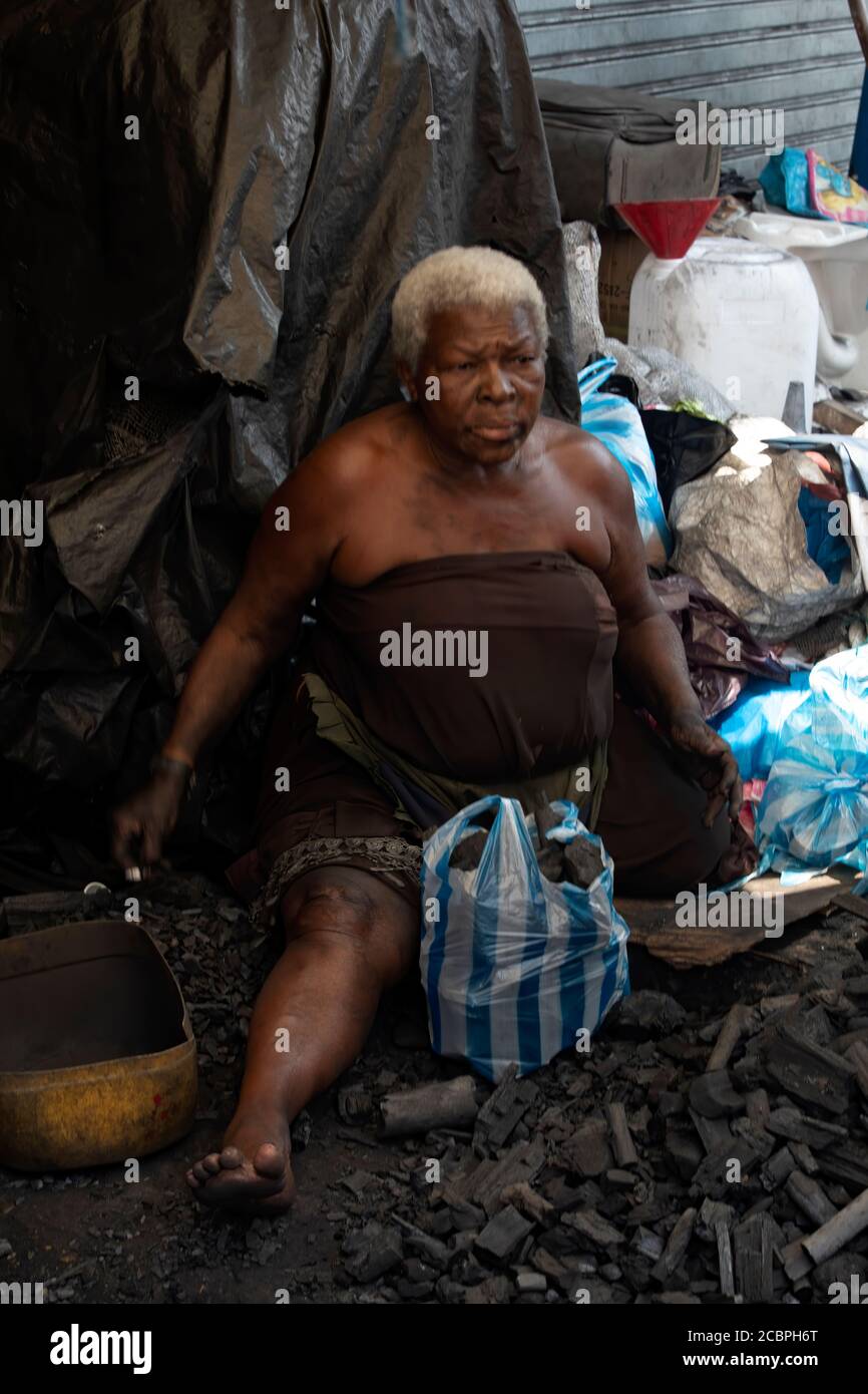 Cartagena Columbia alte Frau verkauft Kohle auf dem Boden. 5065. Historische arme Nachbarschaft Outdoor-Markt. Frisches Obst und Gemüse zum Verkauf. Rohes, frisches Fleisch, Rindfleisch, Schweinefleisch und Fisch, zubereitet unter heißen, unhygienischen Bedingungen. Schmutzige, stinkende Umgebung mit verfaultem Essen. Lokale Restaurants und Einkaufsmöglichkeiten. Stockfoto