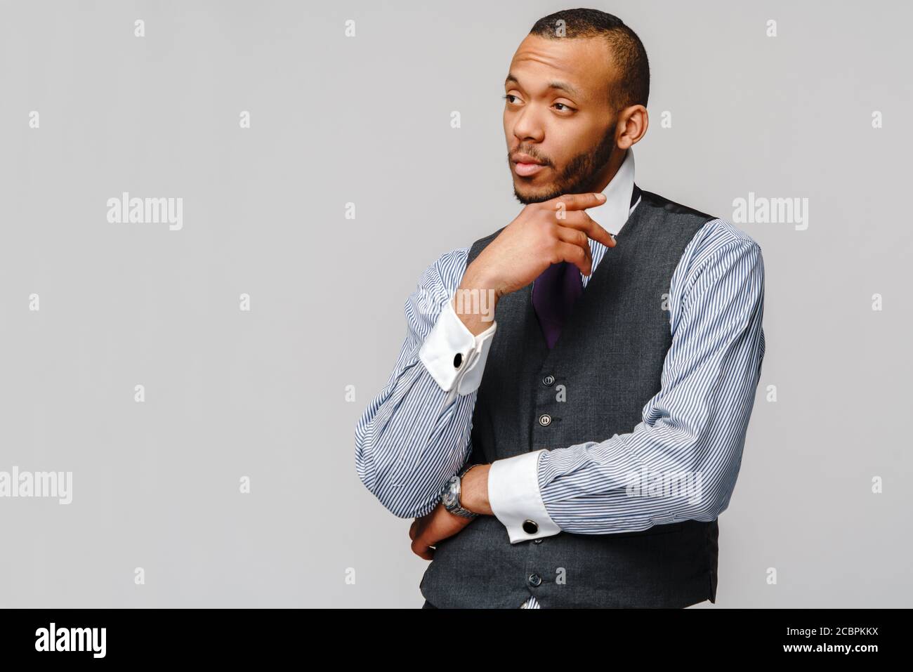 Afroamerikanischer Geschäftsmann, der harte Entscheidung über grauen Hintergrund trifft Stockfoto