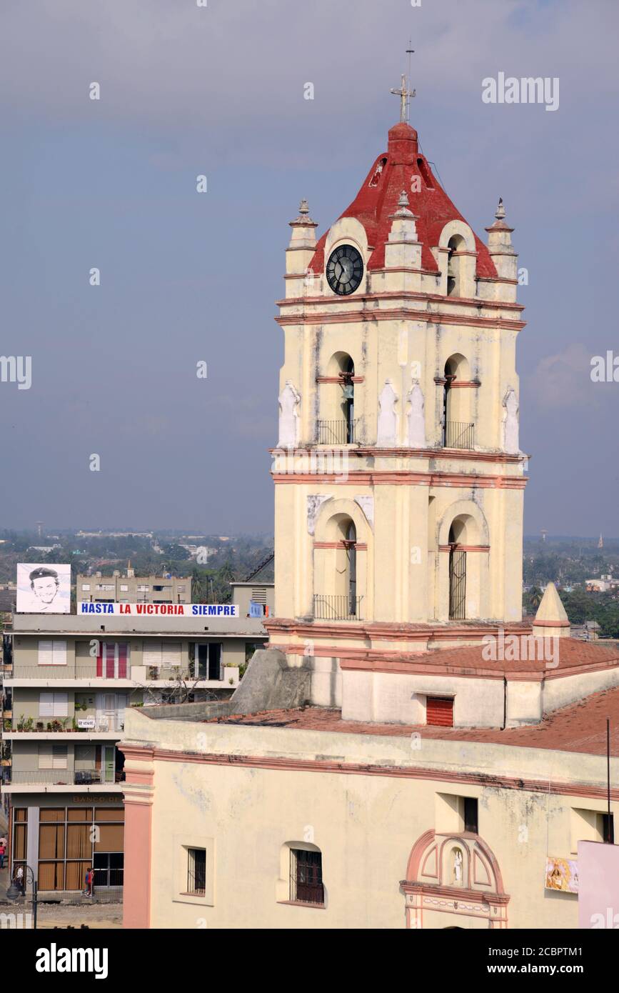 CAMAGUEY, KUBA - 02. März 2013: Eine Kirche in der Stadt Camaguey, Kuba, in der Nähe eines Gebäudes mit einem großen Bild von Che Guevara, zusammen mit einem Schild Stockfoto