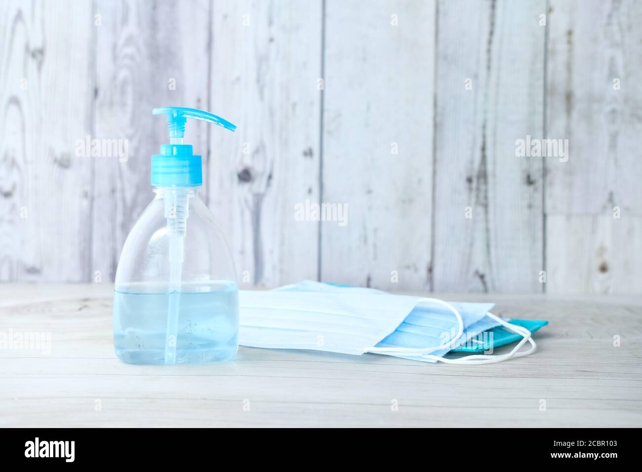 Chirurgische Masken, medizinische Handschuhe und Handdesinfektionsmittel auf Holzhintergrund Stockfoto