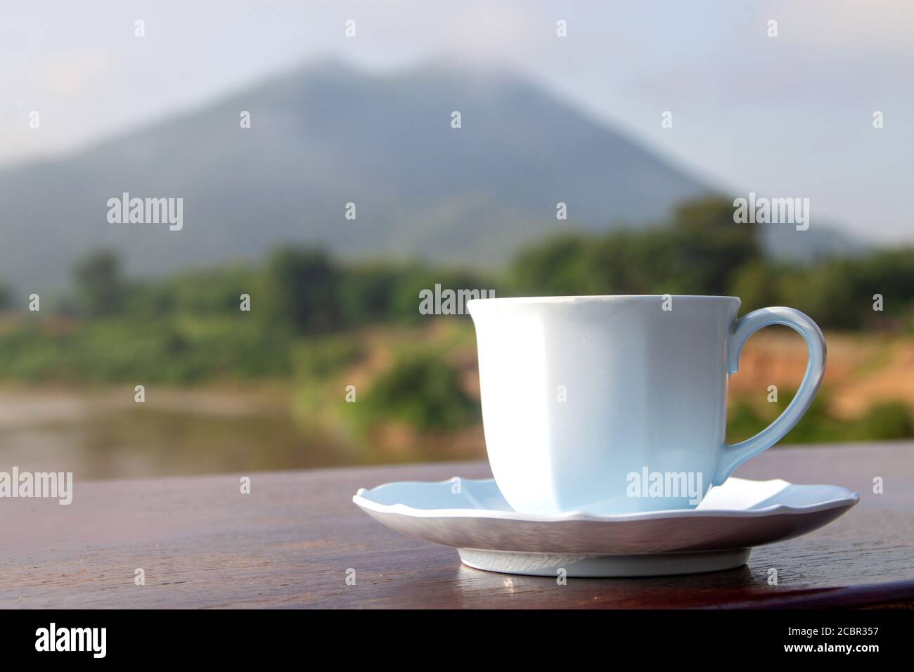 Weiße Tasse Kaffee auf Moutain Hintergrund am Morgen in der Nähe des Flusses. Stockfoto
