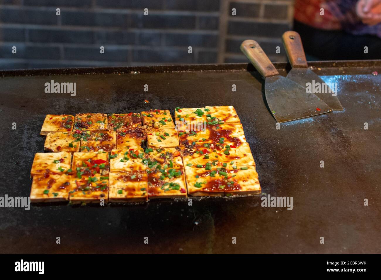 Tofu wird auf einer heißen Platte am Lebensmittelstand auf dem Straßenmarkt in der Altstadt von Luoyang, Luoyang, Provinz Henan, China, zubereitet Stockfoto
