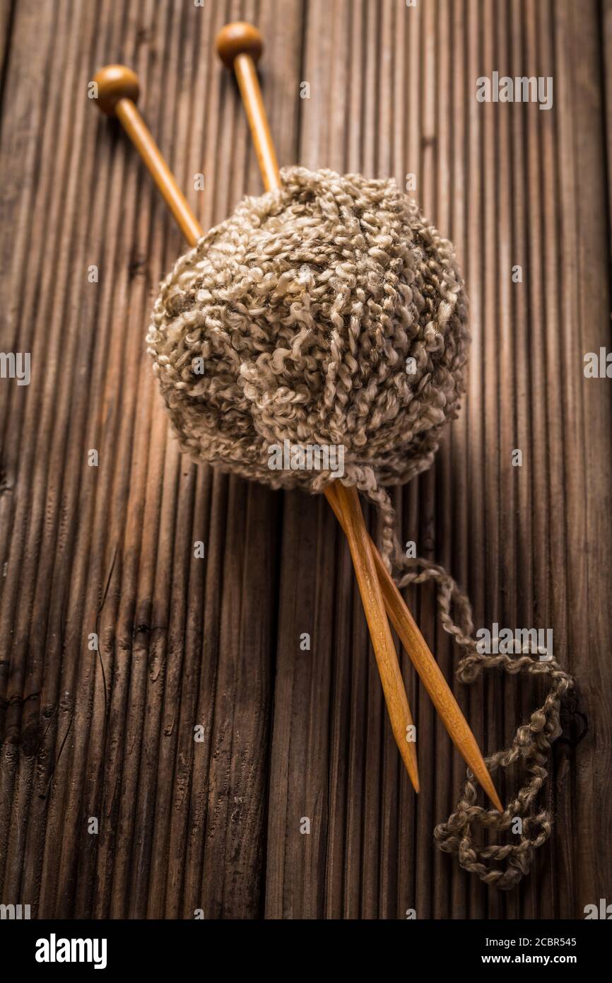 Wollkugel mit Stricknadeln auf Holzhintergrund. Konzept der Handarbeit. Stockfoto