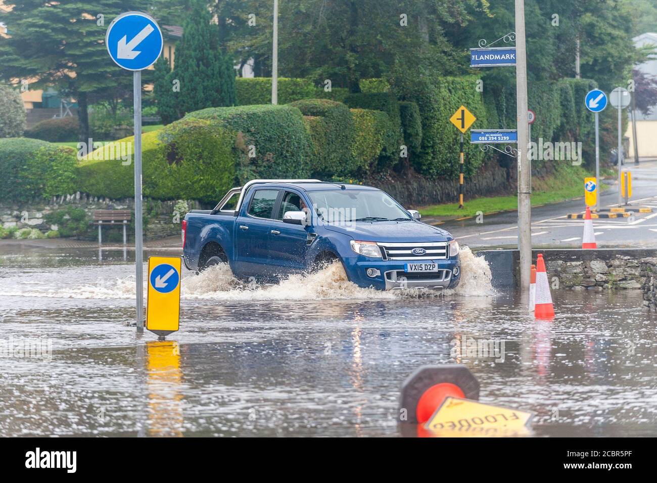 Rosscarberry, West Cork, Irland. August 2020. Die N71-Straße überflutete zum zweiten Mal in drei Tagen über Nacht. Das Landmark Restaurant war sehr stark von Hochwasser getroffen, das die Türen durchschlug. Der bezirksrat ist seit 3 Uhr morgens vor Ort und versucht, die Straße zu räumen. Ein Auto fährt durch die Flut. Quelle: AG News/Alamy Live News Stockfoto