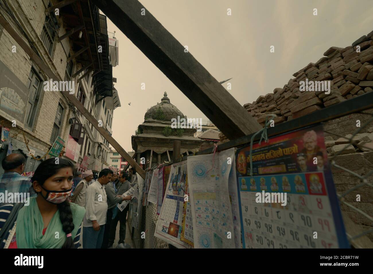 Ein Fußgänger, der auf gedruckte Kalender achtet, die in einer Gasse in Kathmandu, Nepal, zum Verkauf stehen. Stockfoto