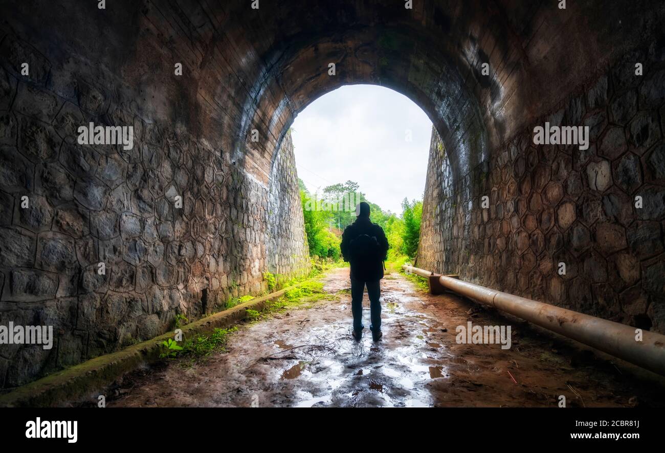 Silhouette Reisende Mann in der alten Eisenbahntunnel erforscht, verlassene Architektur des 19. Jahrhunderts bis heute in der Nähe von Da Lat, Vietnam Stockfoto