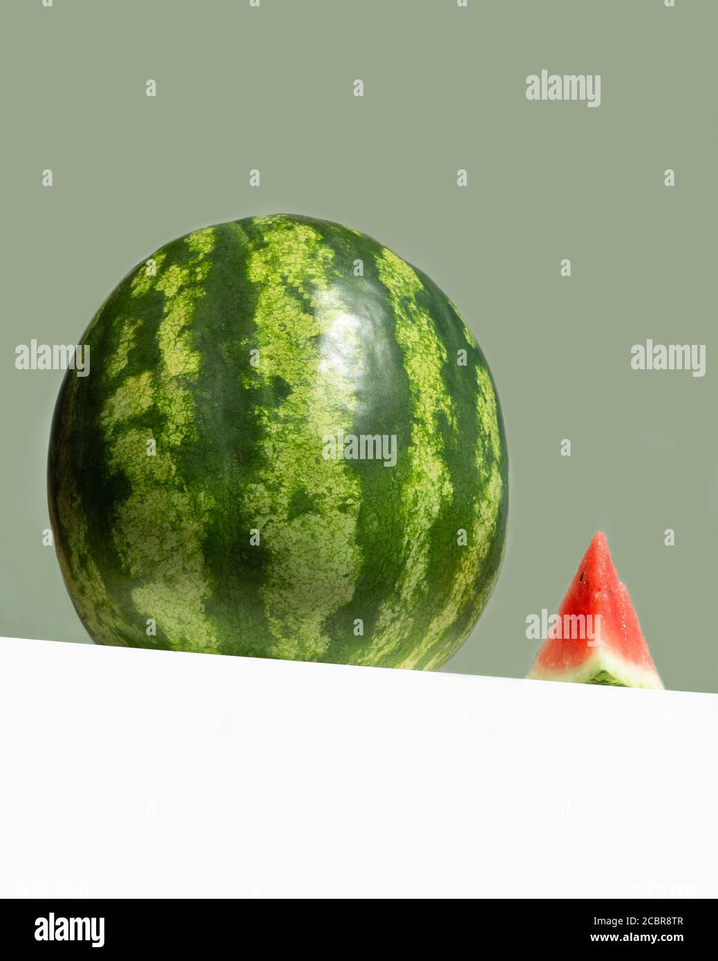 Große frische Wassermelone und rote Scheibe Wassermelone auf Tisch auf neo mint farbigen Hintergrund. Kreative Minimal Sommer Obst-Konzept. Low-Angle-Ansicht Stockfoto