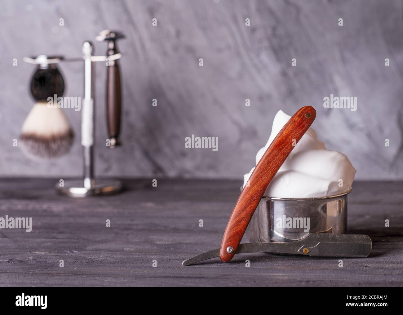 Rasiermesser, Pinsel und Schaum auf einem grauen Holzhintergrund Stockfoto