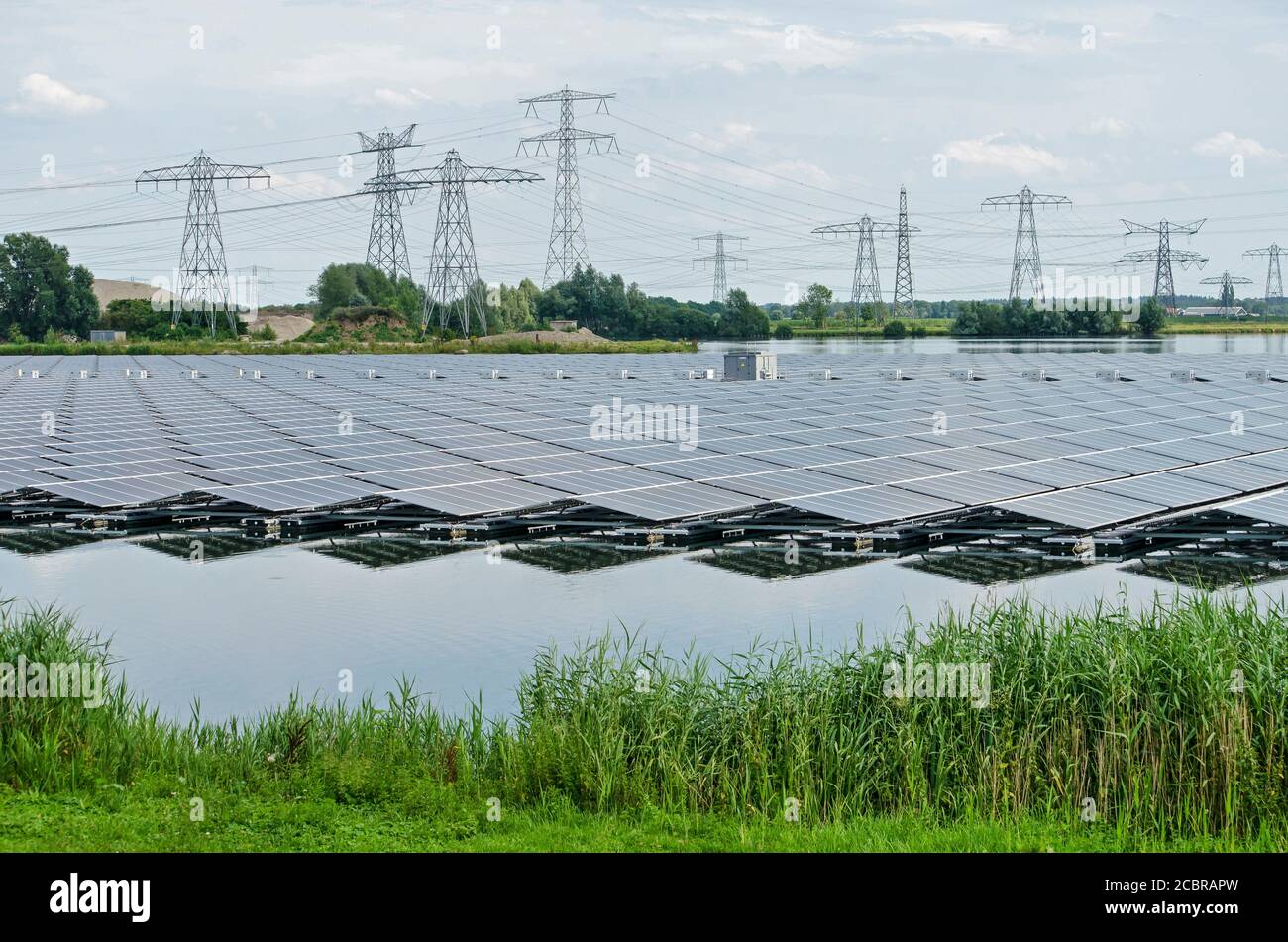 Zwolle, Niederlande, 19. Juli 2020: Im künstlichen See Sekdoorne Plas spiegeln sich zahlreiche Solarmodule mit Strommasten und Strom Stockfoto