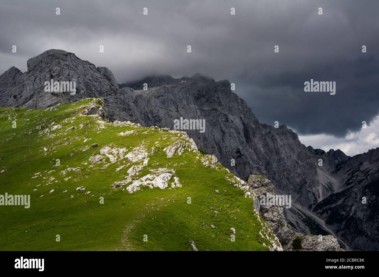 Kamnik Sattel ( Kamnisko sedlo ), Kamnik-Savinja Alpen, Slowenische Alpen, Slowenien, Europa - die Oberseite des Sattels ist mit grünem Gras bedeckt. Hohe Berge duri Stockfoto