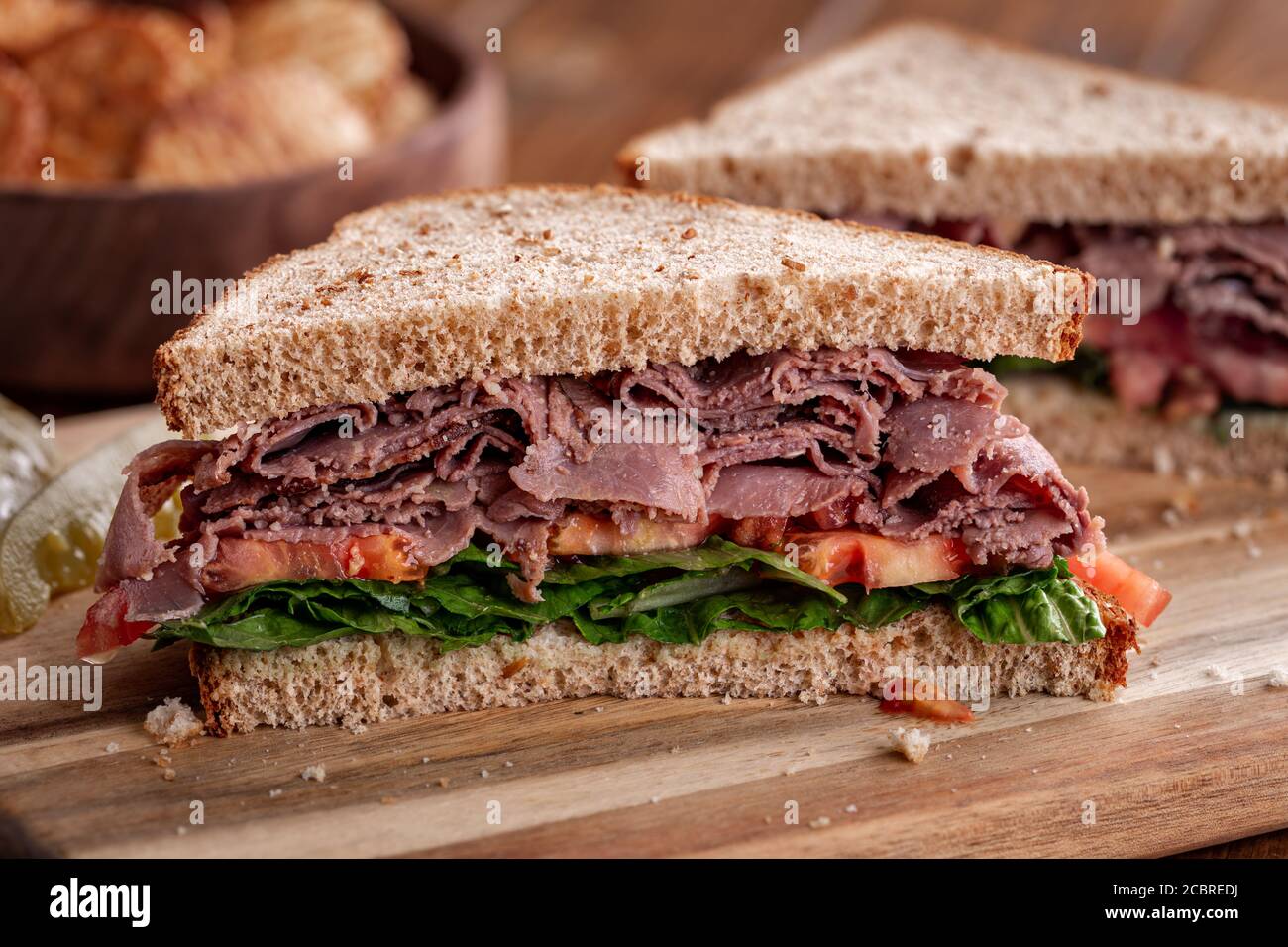 Nahaufnahme von Roastbeef Sandwich mit Salat und Tomaten auf Vollkornbrot in zwei Hälften geschnitten Stockfoto