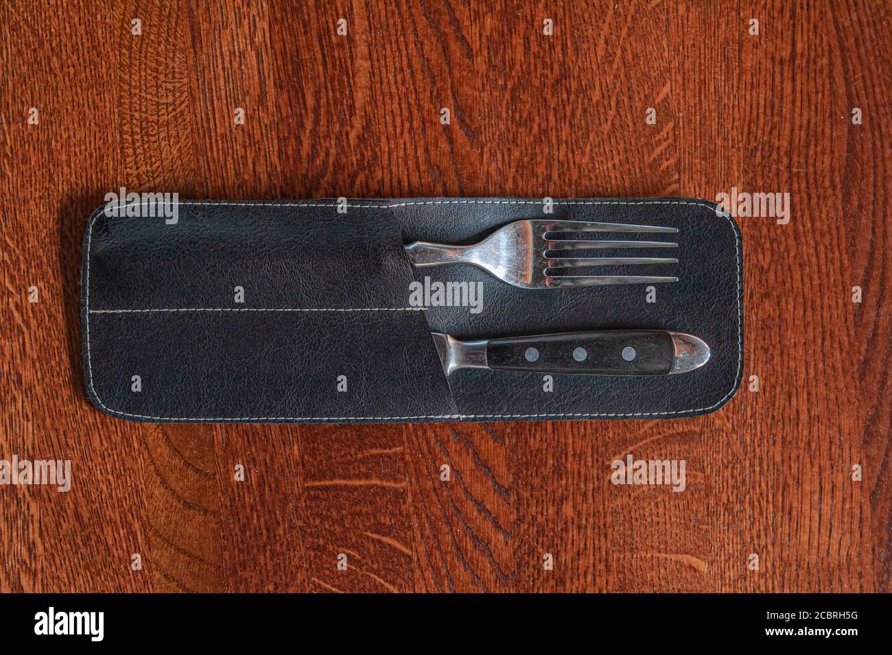 Restaurant Besteck eine Gabel und Messer in einem speziellen schwarz Lederetui liegen auf einer Holztischoberfläche Stockfoto