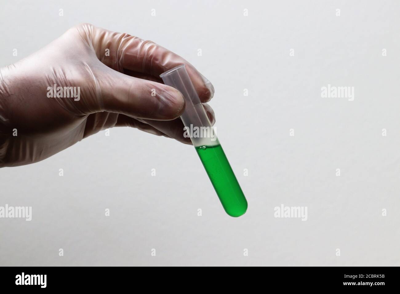 Hand hält ein Reagenzglas mit grüner Flüssigkeit Stockfoto