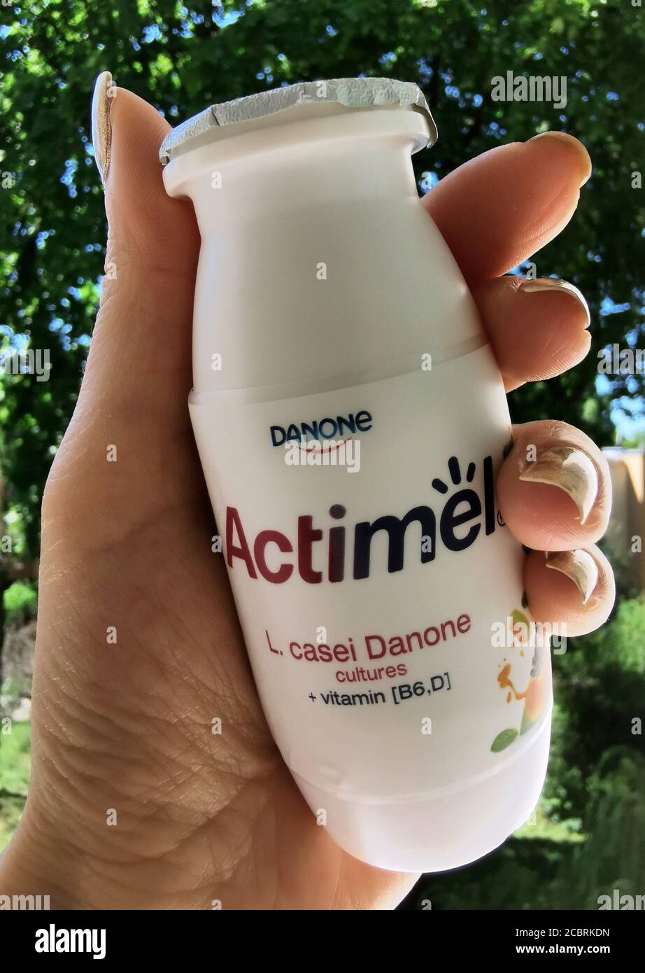 Actimel Joghurt in der Hand auf dem Hintergrund von Bäumen Stockfoto