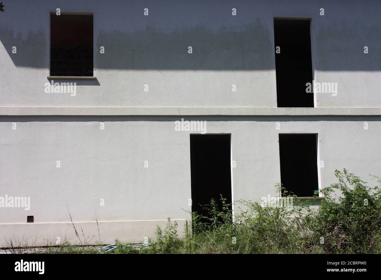 Fehlende Fenster und Tür zu einer Fassade von einem alles Weißes verlassenes Haus renovierungsbedürftig Stockfoto