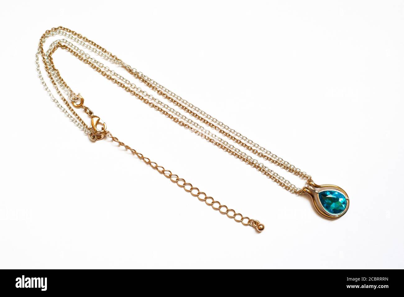 Silberne goldene Halskette mit einem blauen Stein auf einem weißen Hintergrund Stockfoto