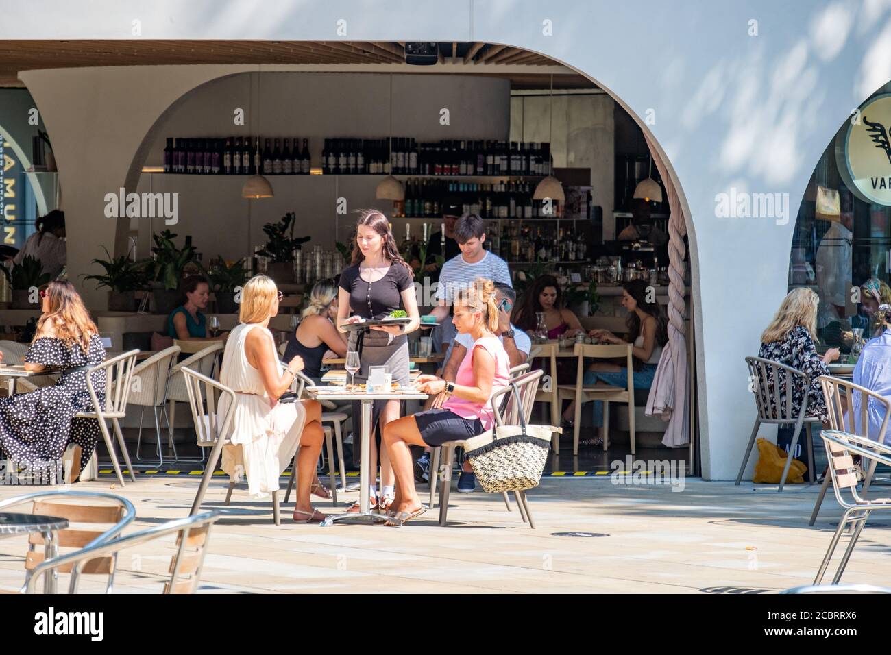 London - August 2020: Kellnerin bedient Kunden in einem Restaurant im Freien auf dem Duke of York Square an der Kings Road, Chelsea Stockfoto