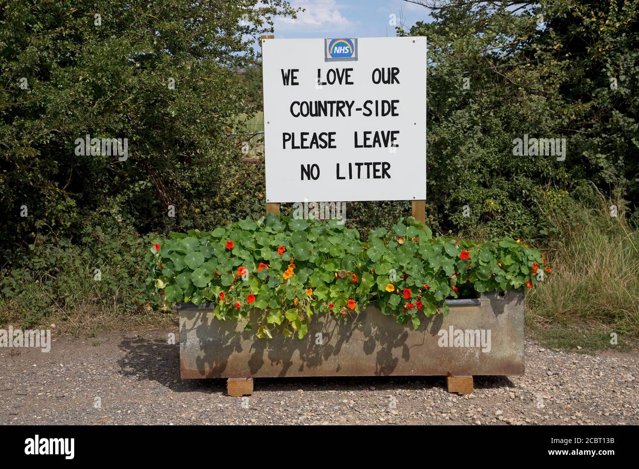 Bitte lassen Sie keinen Abfall - wir lieben unsere Landschaft beachten Mit NHS-Logo im Layby in alten Trinkrinnen montiert Voller Blumen in der Nähe von Stratford upon Avo Stockfoto