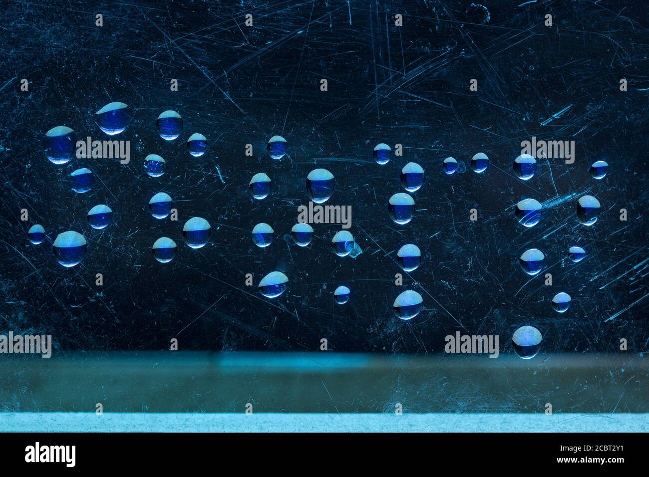 Wort beängstigend von Wassertropfen auf der Oberfläche von Eine geheimnisvolle Atmosphäre aus zerkratztem Glas Stockfoto