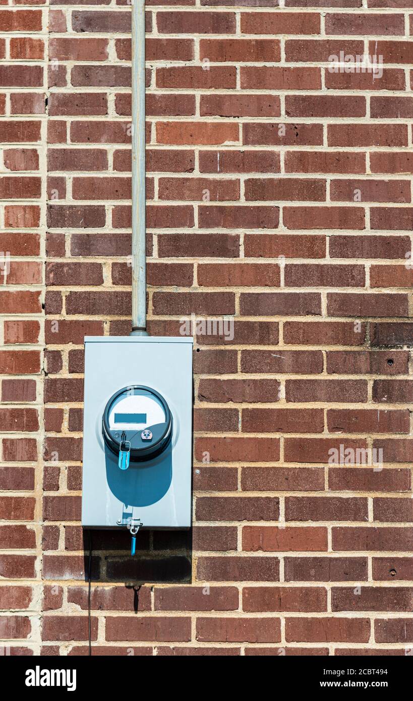 Vertikale Aufnahme eines elektrischen Zählers auf einer alten roten Ziegelwand. Speicherplatz kopieren. Stockfoto