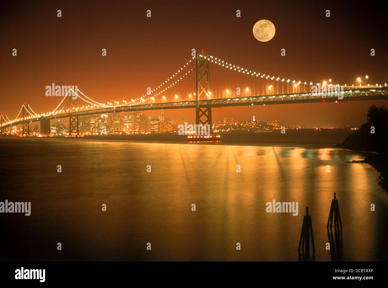 Oakland Bay Brücke bei Sonnenuntergang bei Vollmond mit San Francisco Skyline über der Bucht Wasser... Stockfoto