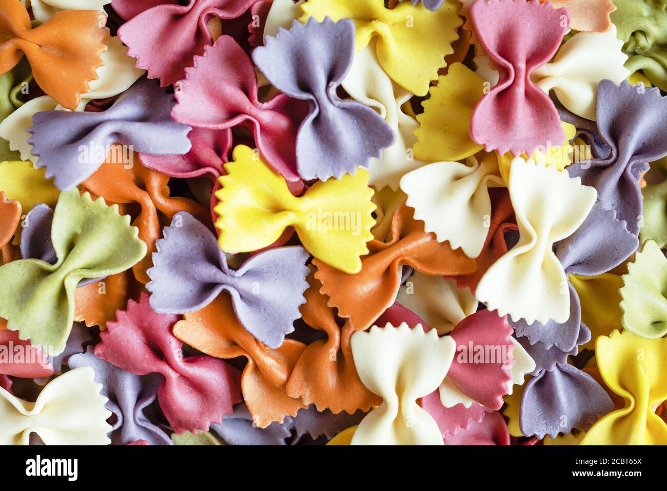 Bunte Farfalle Pasta Hintergrund. Rohe Bio-Farfalle. Traditionelle italienische Farfalle Pasta. Italienische Küche. Fliege Nudeln. Ungekochte getrocknete Farfall Stockfoto