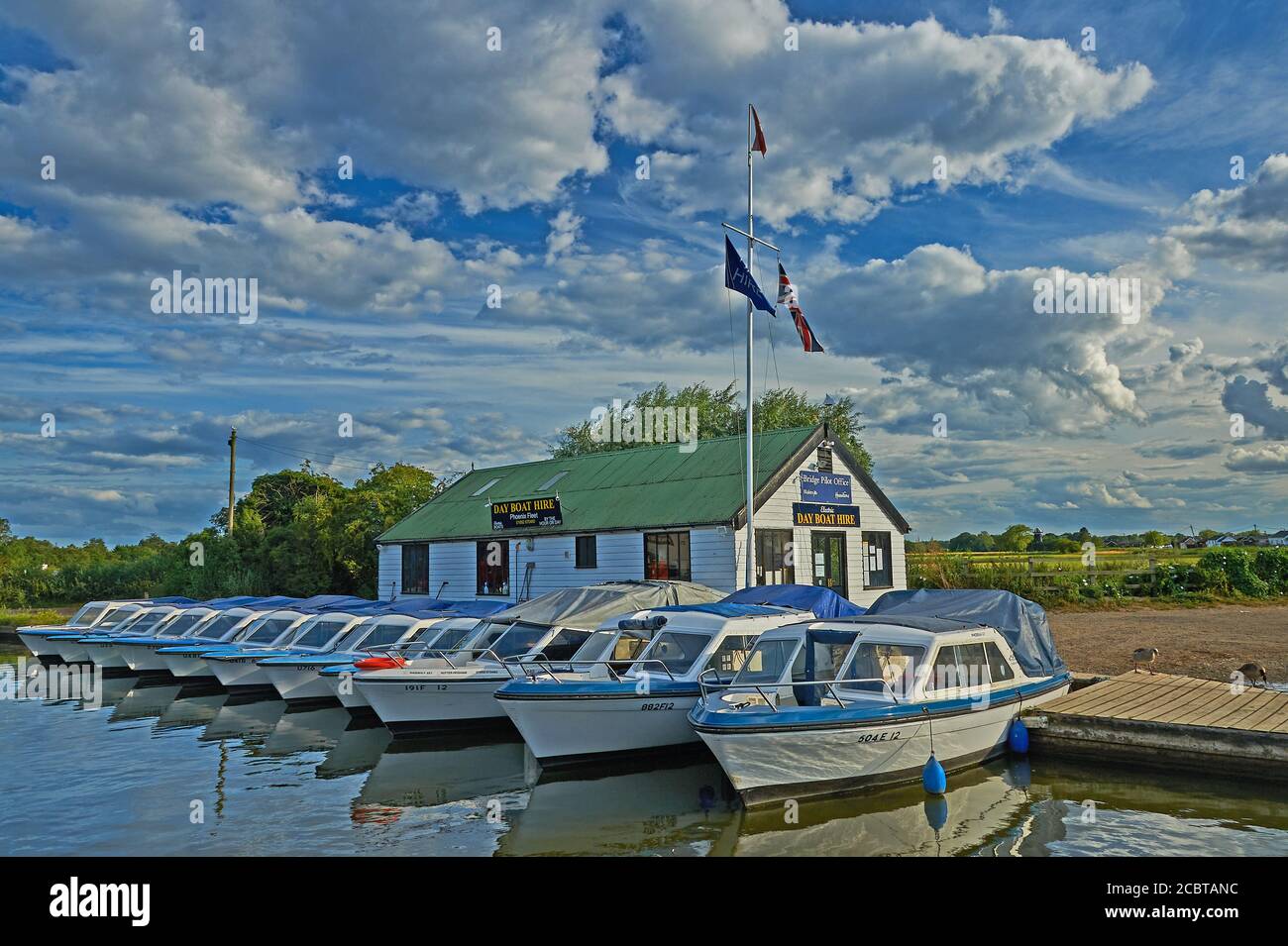 Elektrische Tagesmiete Boote Reihen sich an der Staithe in Potter Heigham, Norfolk Broads National Park, Norfolk. Stockfoto