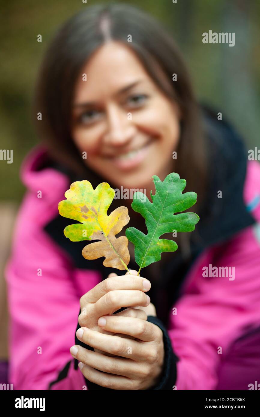 Mädchen in rosa hält zwei Herbstblätter. Herbstsaison in den Bergen. Konzentrieren Sie sich auf Blätter. Stockfoto