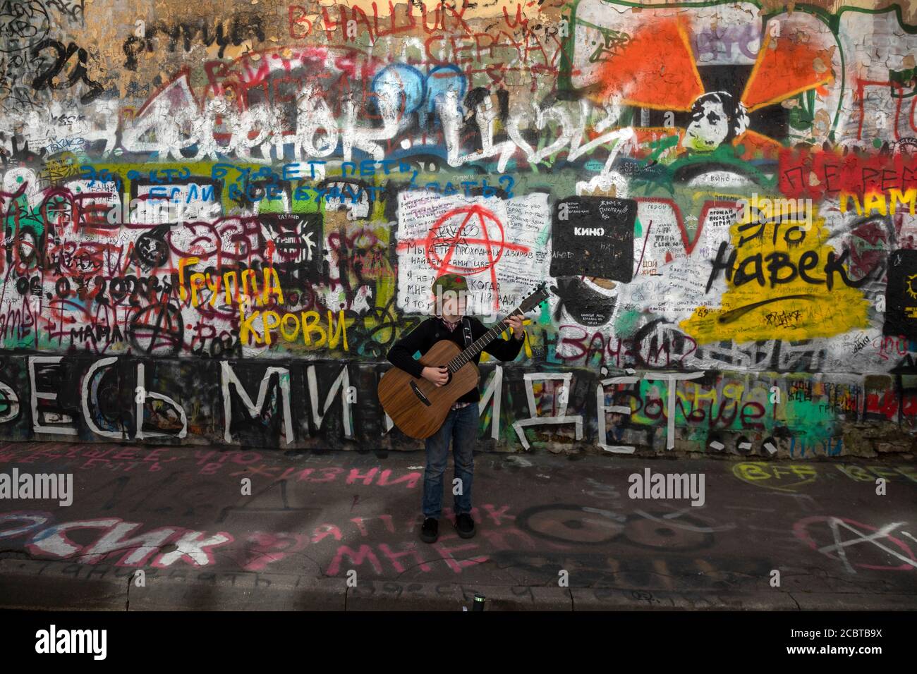 Moskau, Russland. 15. August 2020 EIN kleiner Fan von Viktor Tsoi singt ein Lied mit Gitarre auf dem Hintergrund der Tsoi-Mauer in der Arbat-Straße in Moskau am 30. Todestag des Sängers, Russland. Die Tsoi Wall ist eine mit Graffiti bedeckte Wand in Moskau, die dem Musiker Viktor Tsoi und seiner Band Kino gewidmet ist Stockfoto