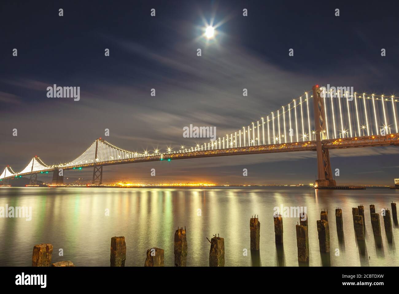 Der Mond steigt bei Einbruch der Dunkelheit über die San Francisco Bay Bridge, Kalifornien, USA. Stockfoto