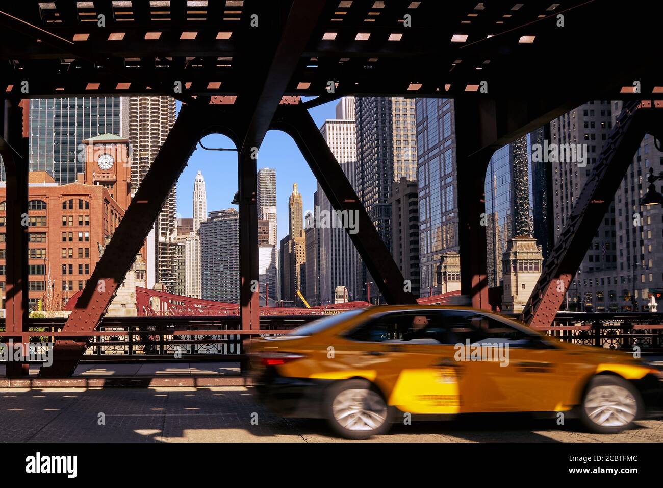 Gelbes Auto, das über eine Brücke zum Stadtzentrum von Chicago fährt Im Hintergrund Stockfoto