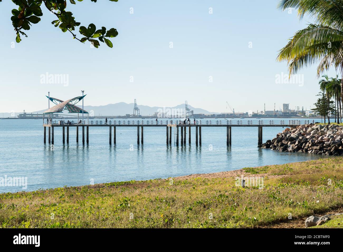 Fischer am Morgen an einem warmen Wintertag auf dem Strand Steg, Townsville mit dem Hafen dahinter Stockfoto