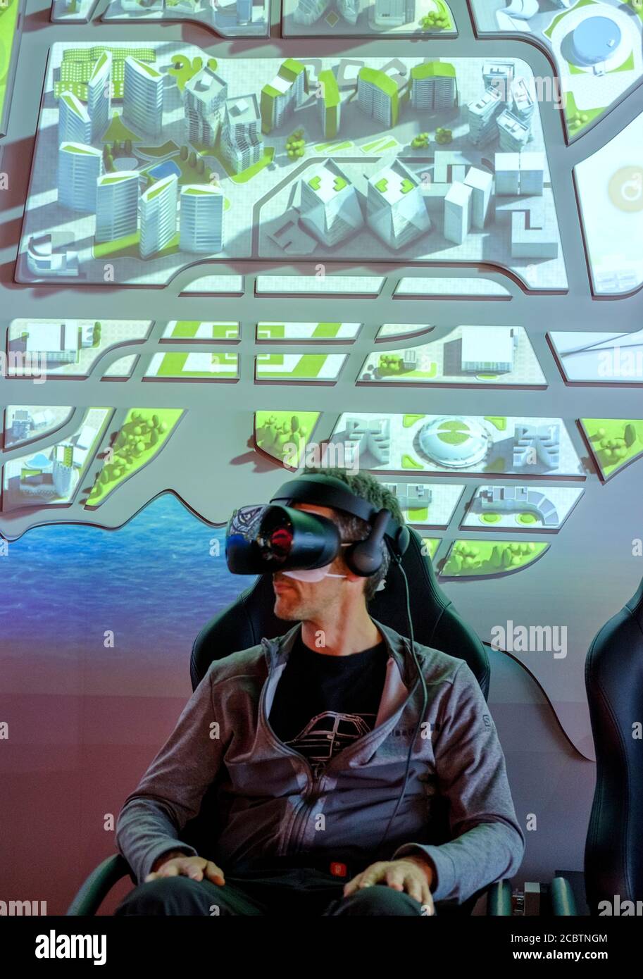 Mann in VR-Brille sitzt auf einem Stuhl genießen virtuelle Reality Demonstration im TSMC Museum Stockfoto