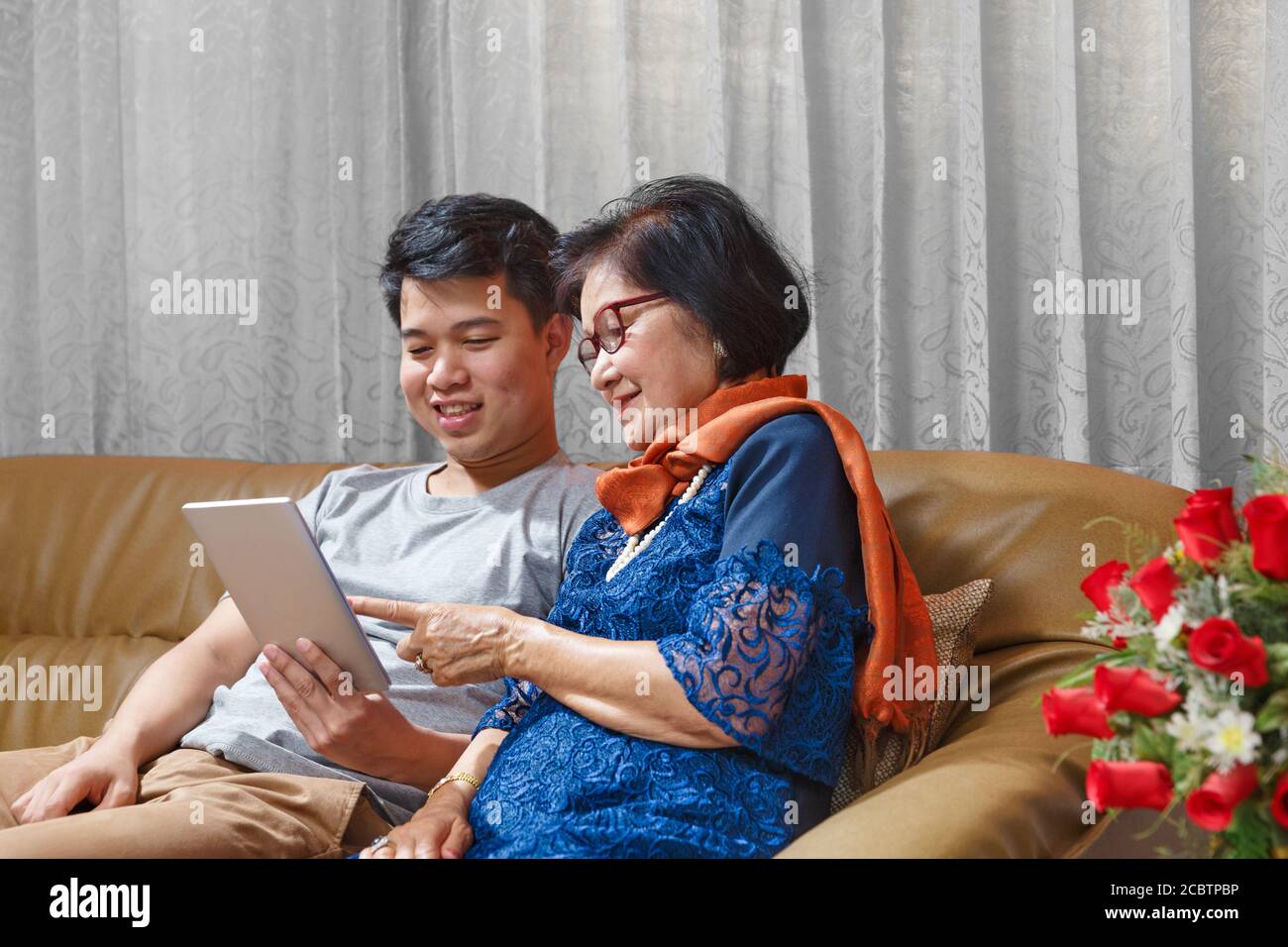 Erwachsene Sohn und ältere Mutter singen ein Lied, während entspannt Sitzen auf der Couch Stockfoto