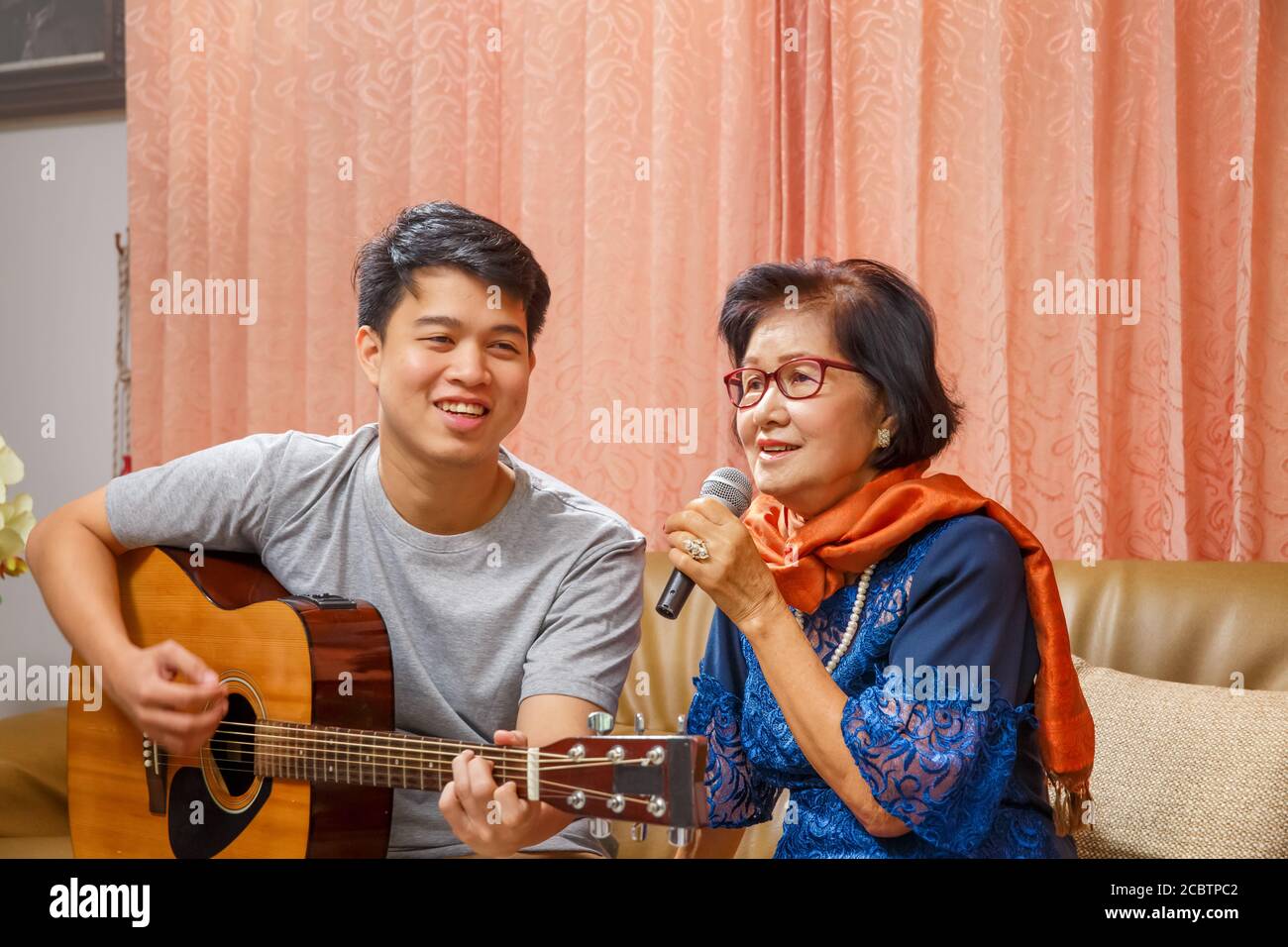 Erwachsene Sohn und ältere Mutter singen ein Lied, während entspannt Sitzen auf der Couch Stockfoto