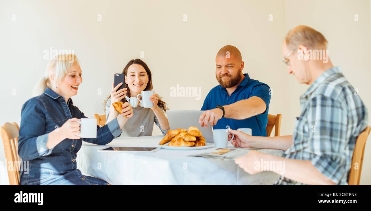 Happy Multi-Generationen-Familie Lesen Nachrichten am Morgen während Beim Frühstück Stockfoto