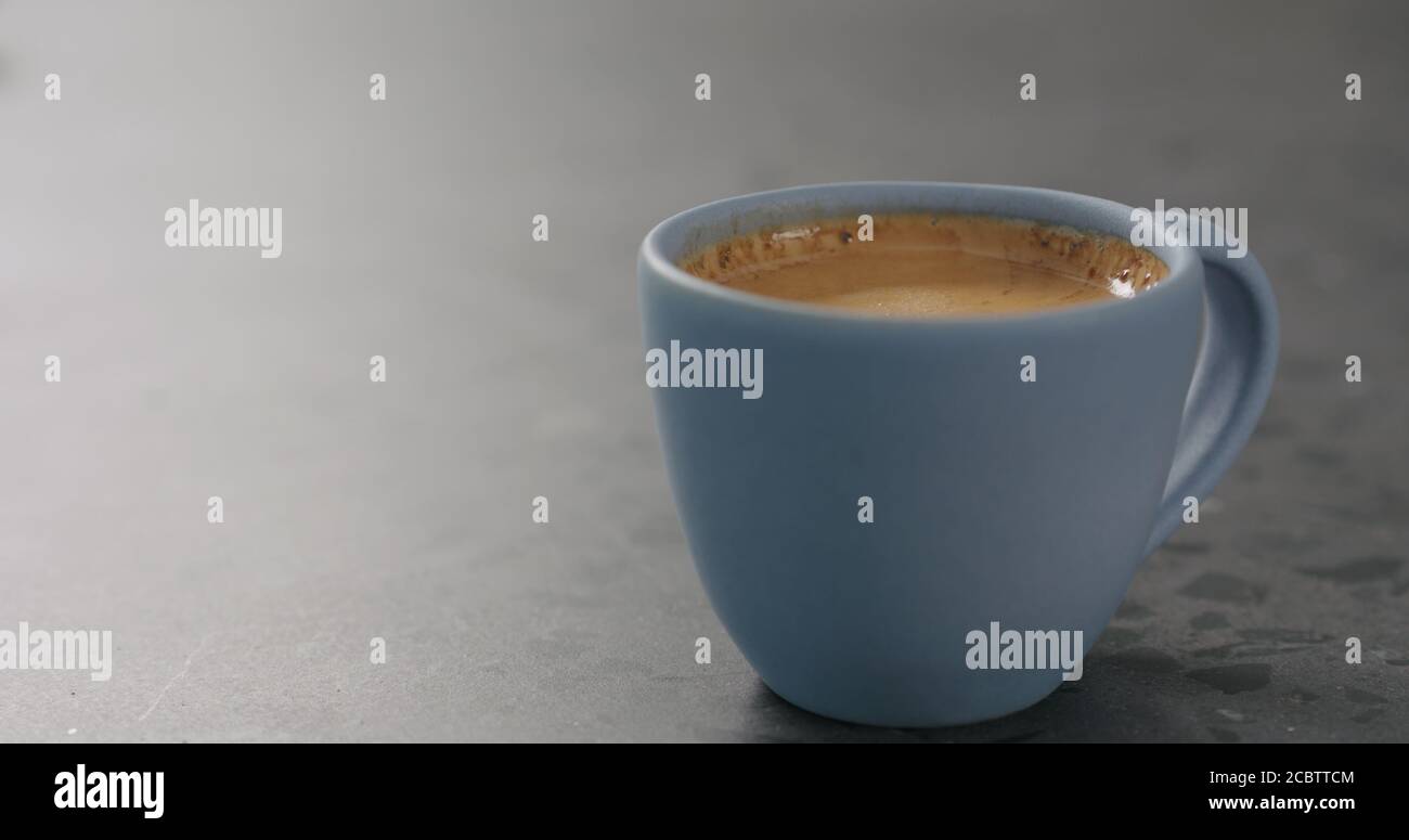 Blaue Tasse mit frischem Espresso auf Betonoberfläche, breites Foto Stockfoto