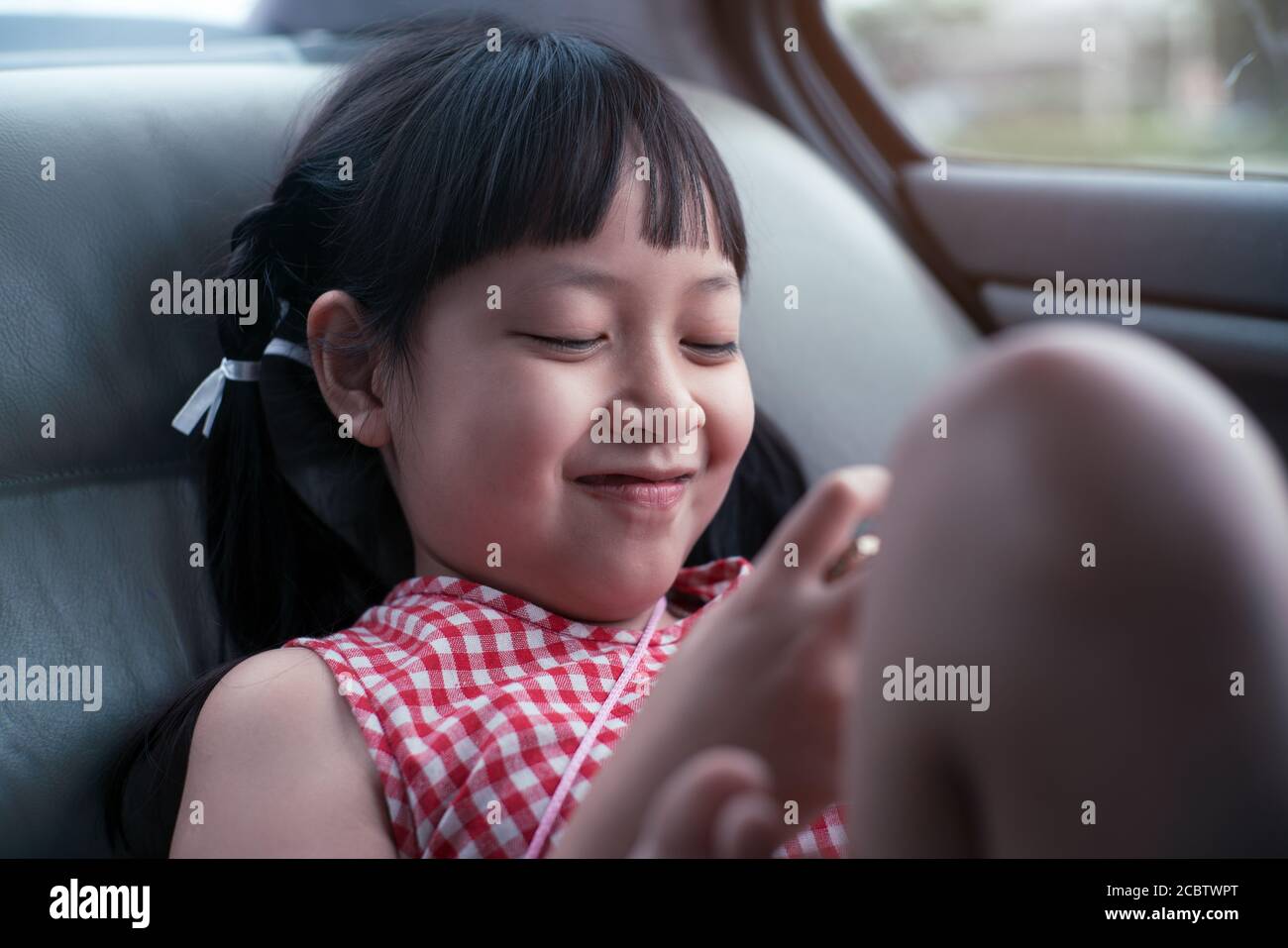 Asiatische Kind Mädchen spielen mit Smartphone im Auto Stockfoto