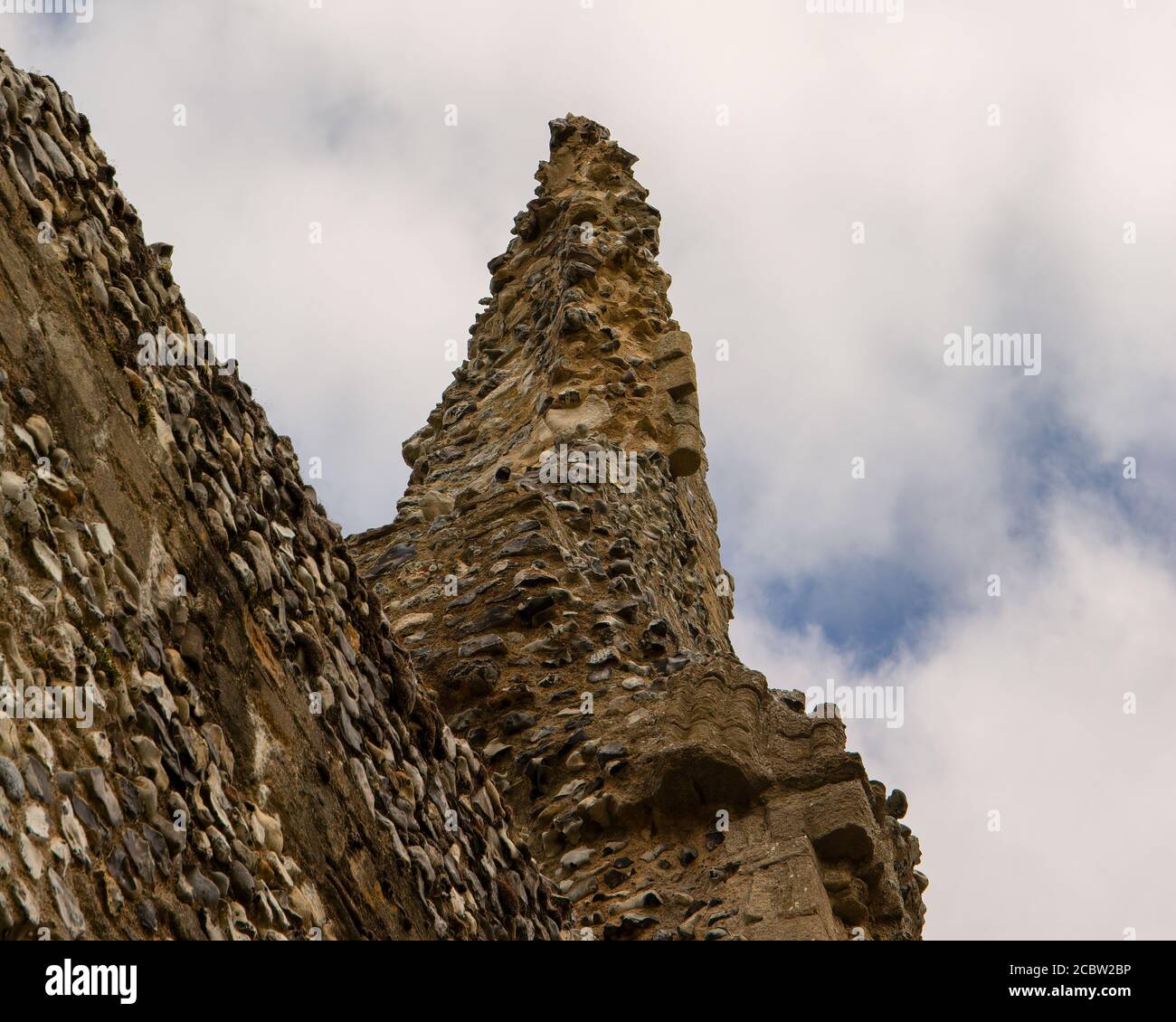 Überreste eines gewölbten Turms in einer mittelalterlichen Mauer aus verwittertem Feuerstein. Stockfoto